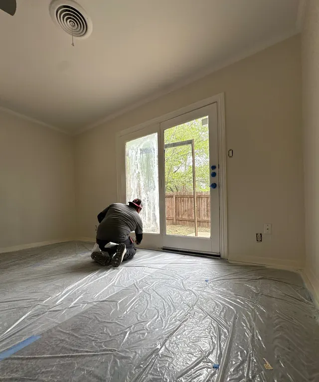 Crew member kneeling to caulk and paint a patio door frame