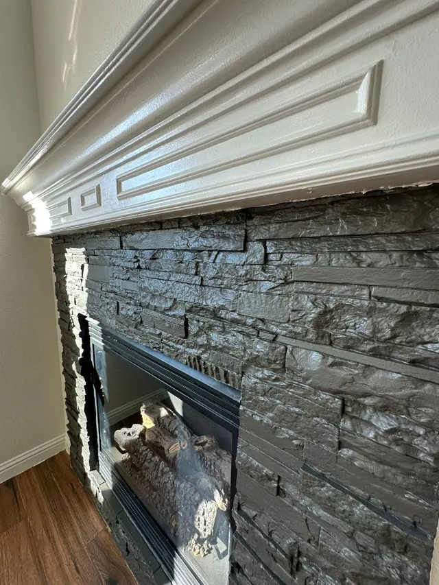 Close-up of a painted charcoal stone fireplace under a white mantel