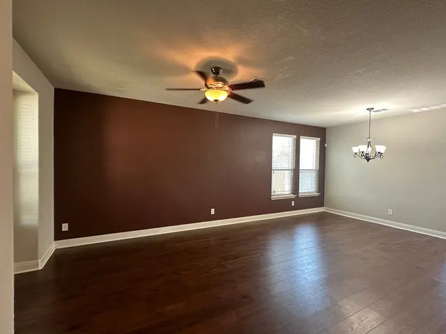Empty living room with a deep brown accent wall and dark plank floors